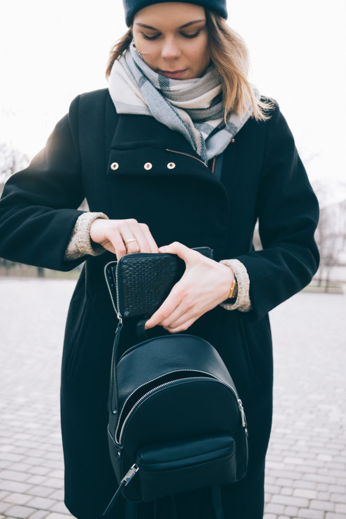 A woman in a coat reaching in to her purse