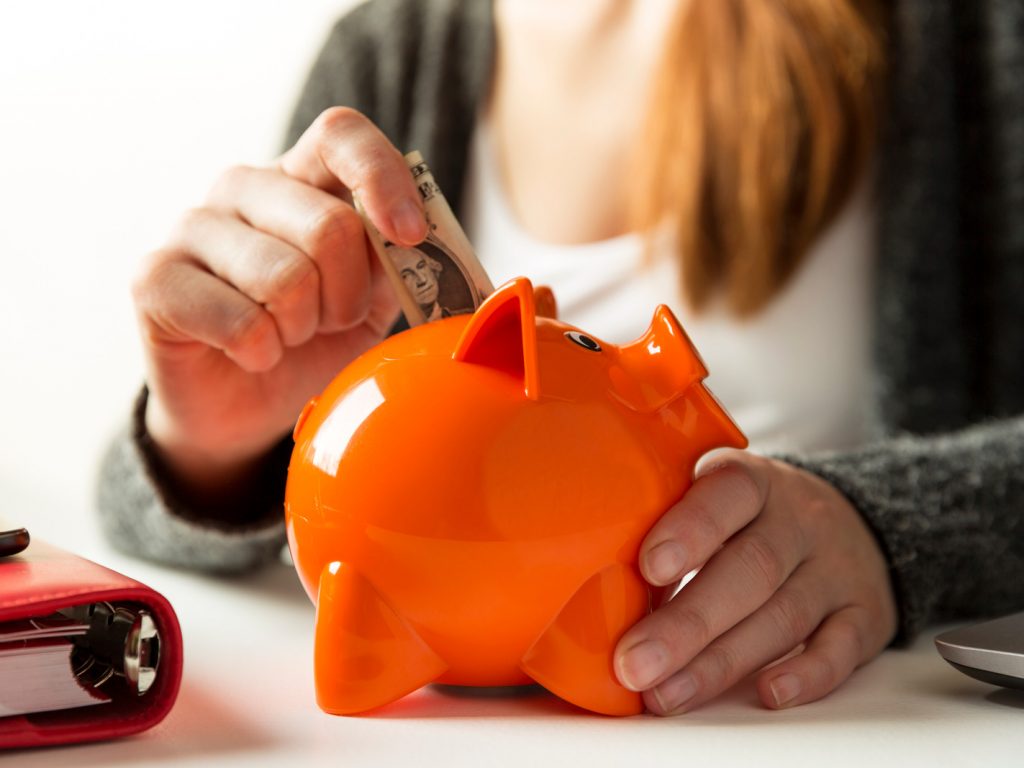 Woman putting a dollar into a piggy bank